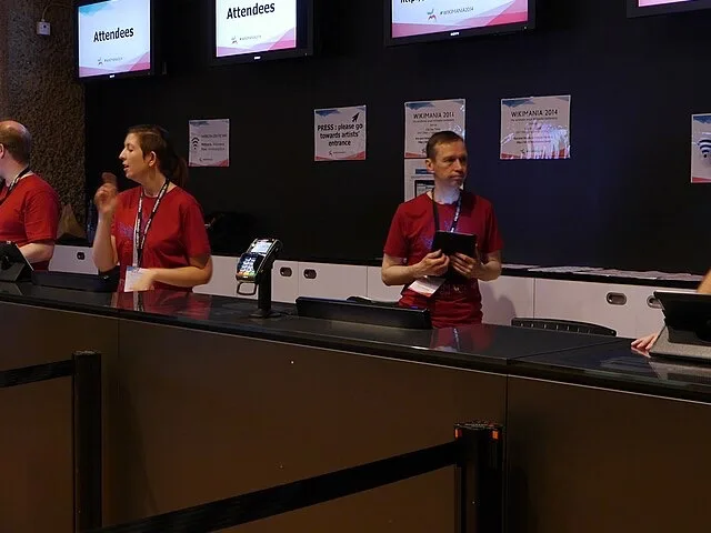 Rendezvényszervezők a regisztrációs pultnál fogadják a résztvevőket egy konferencián